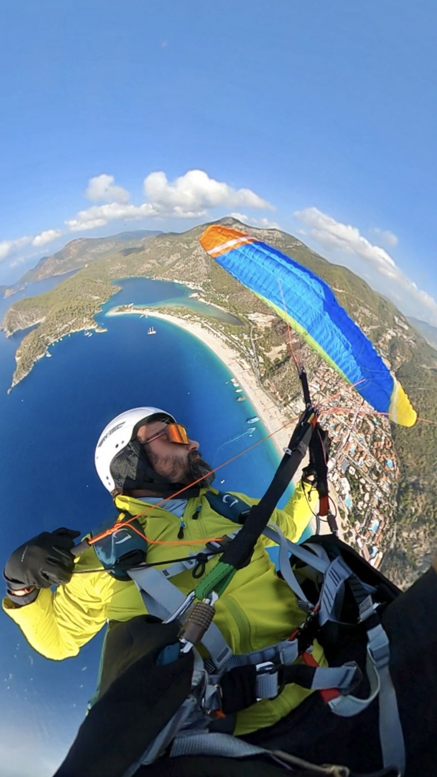 Acrobatic move with paraglider, high above the sea by beach  